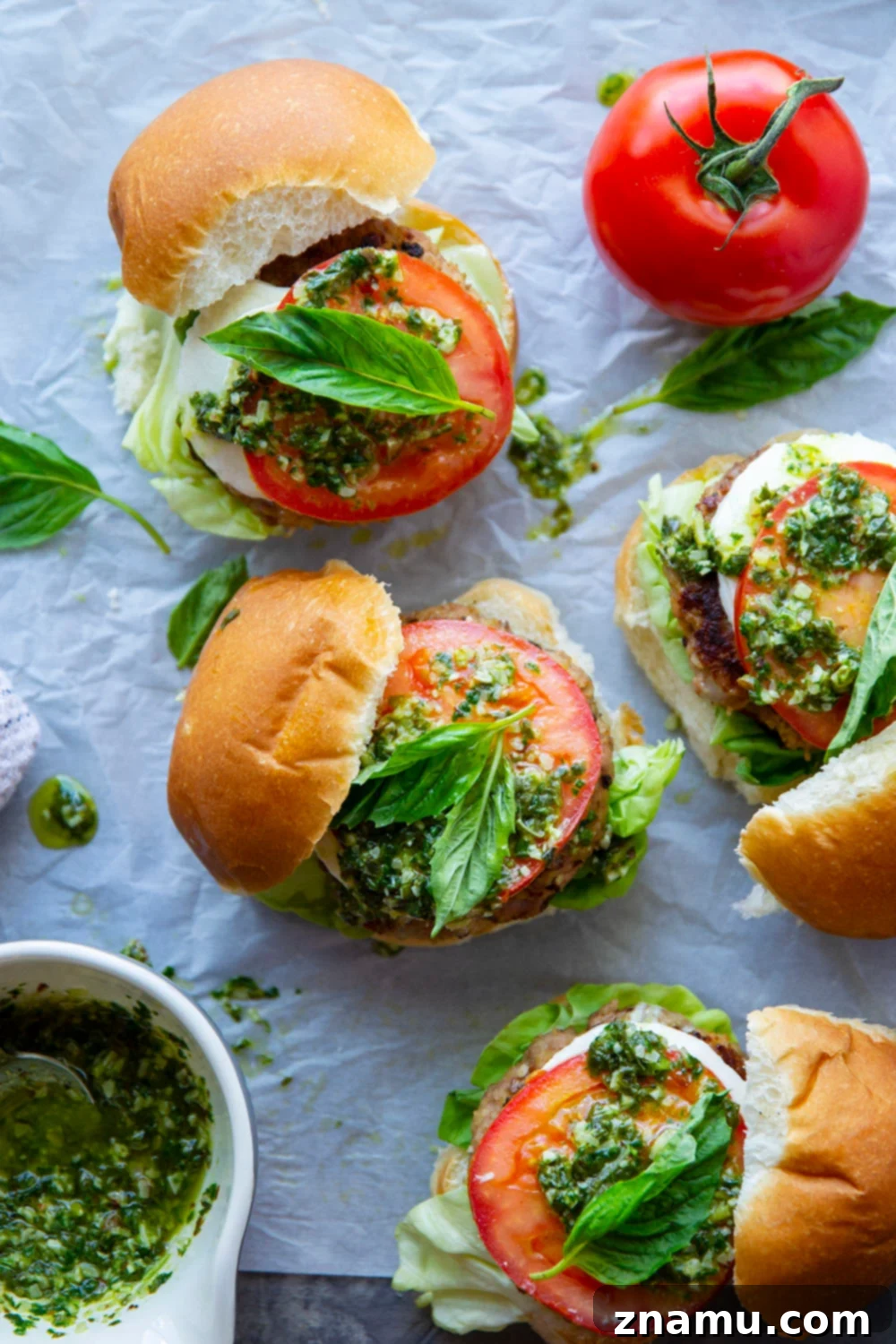 These Caprese Chicken Burgers are perfectly juicy and dressed up with all the caprese fixings and a flavorful pesto vinaigrette drizzled on top.
