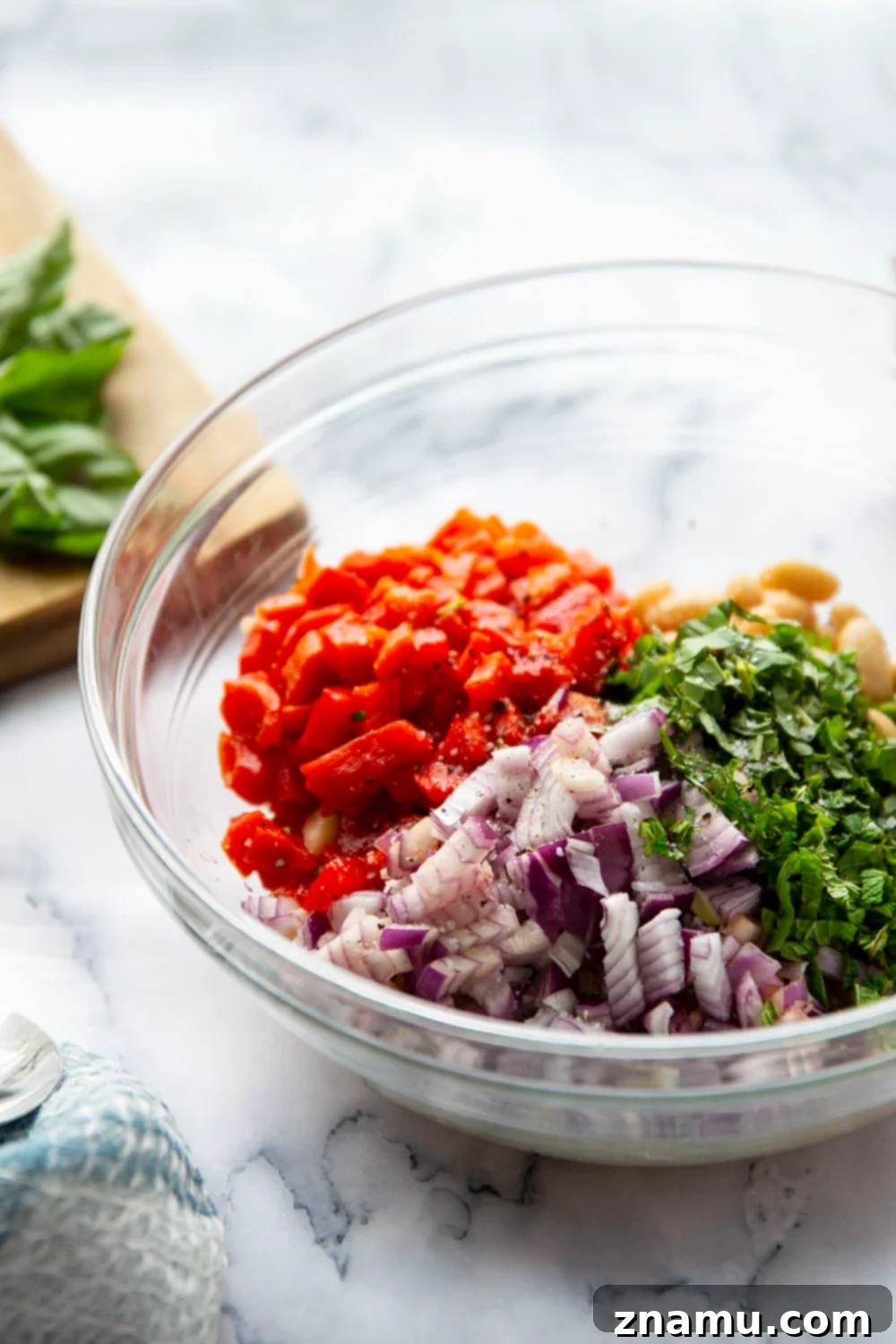 Miso Infused White Bean & Roasted Red Pepper Salad 4 Ingredients for white bean salad laid out, including cans of cannellini beans, a jar of roasted red peppers, fresh basil, mint, and red onion.