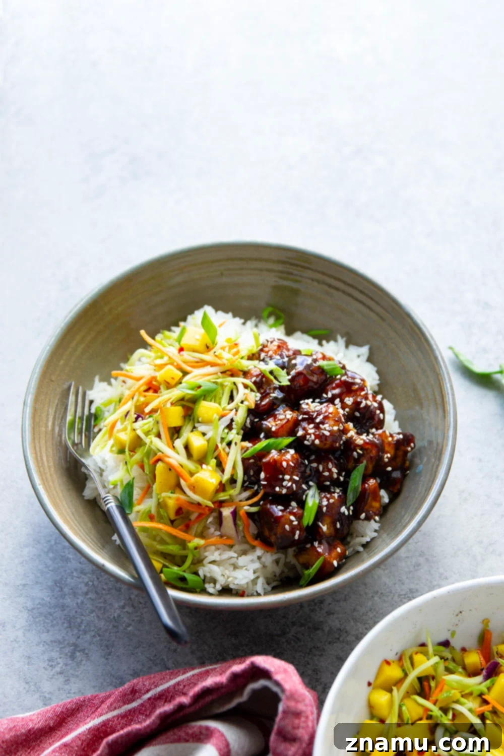 Smoky Korean BBQ Tofu Bowls with Spicy Mango Slaw 2 Korean BBQ tofu bowls feature perfectly crisp and saucy tofu piled over fluffy rice with a sweet and spicy mango slaw on top.
