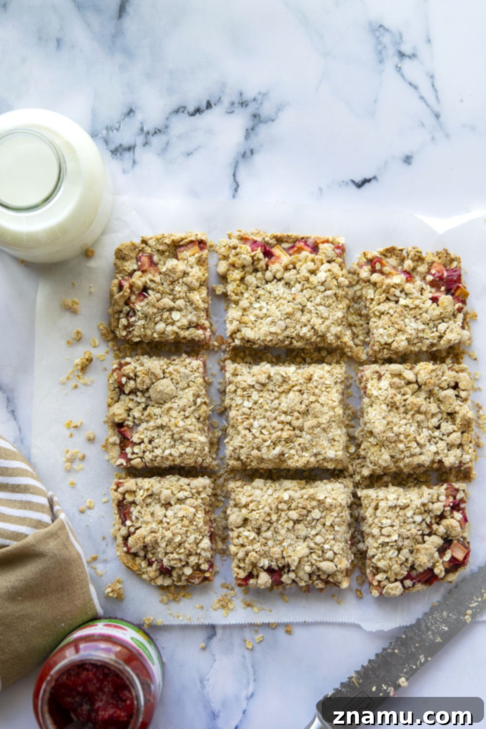 Summer Raspberry Rhubarb Crumble Bars 4 A stack of three raspberry rhubarb oatmeal bars, showing off the thick layers of crust, filling, and streusel.