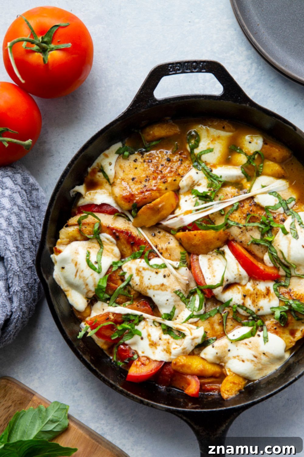 One-Pan Peach Caprese Chicken 2 Close-up of Skillet Caprese Peach Chicken with seared chicken, melted mozzarella, peach slices, tomatoes, and fresh basil.