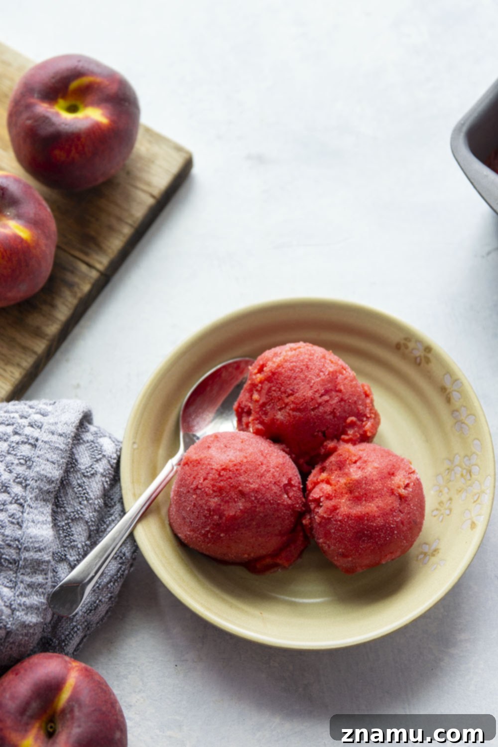 Refreshing Peach Cherry Sorbet 6 Three scoops of peach cherry sorbet in a bowl, garnished with fresh mint and a few whole cherries, emphasizing its readiness to serve.