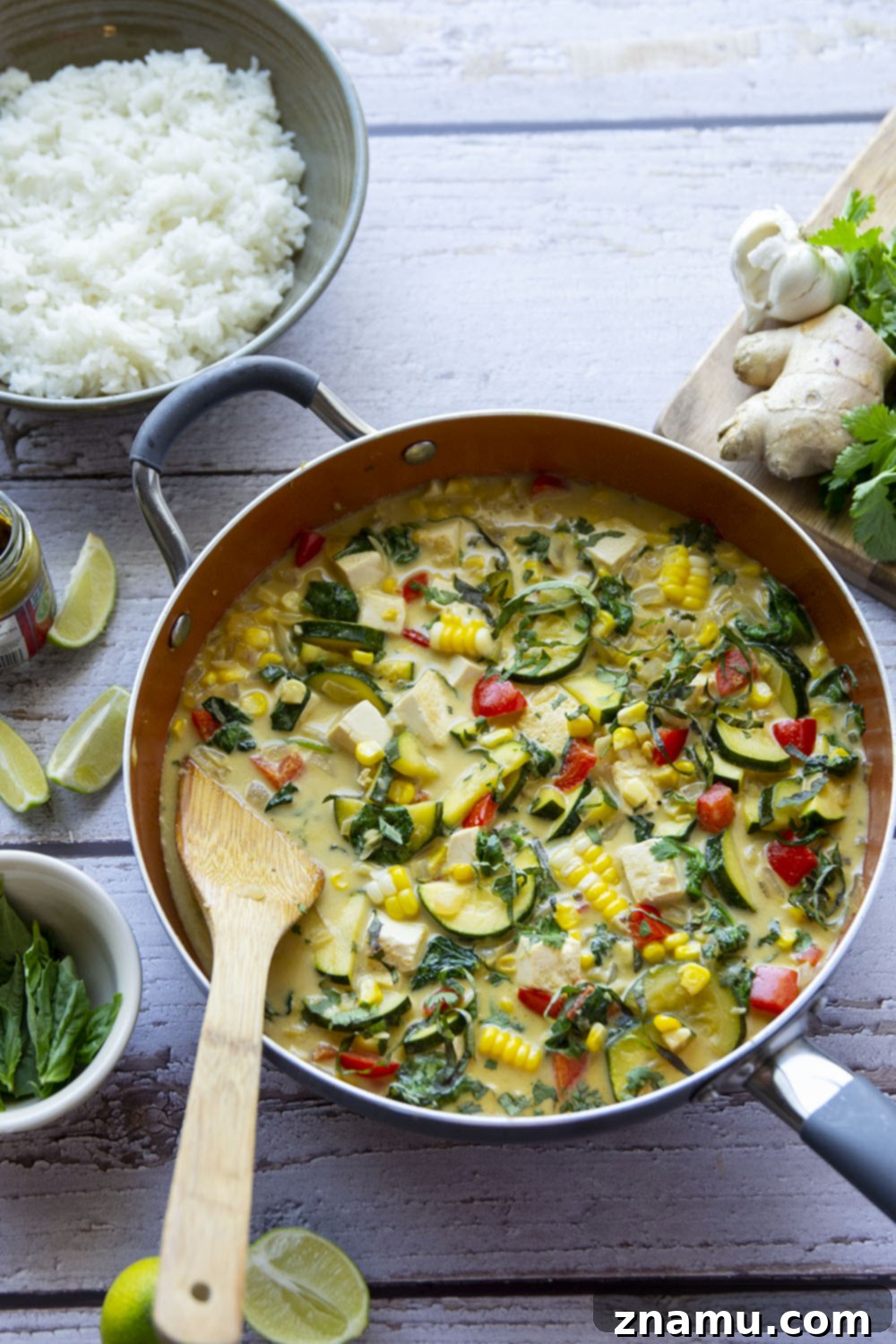 Overhead shot of a skillet filled with colorful Thai green curry tofu and vegetables.