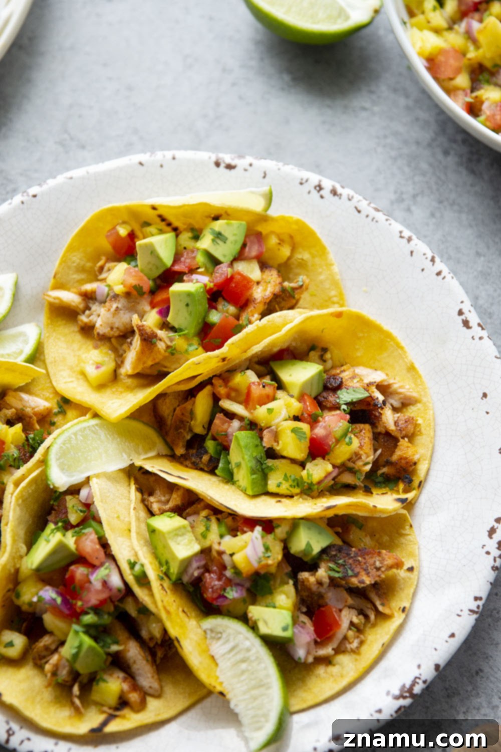 Smoky Salmon Tacos with Bright Pineapple Salsa 4 Prepared ingredients for Blackened Salmon Tacos, including blackened salmon fillets, fresh pineapple salsa, and avocado slices.