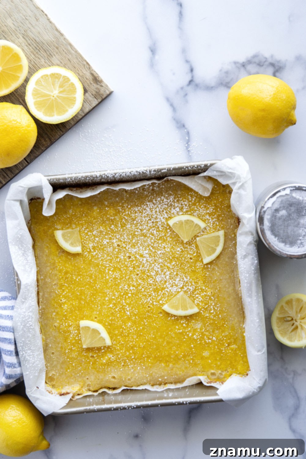 Perfect Lemon Bars 3 Close-up shot of freshly baked lemon bars, showing the thick, golden shortbread crust and the glossy, pale yellow lemon custard.