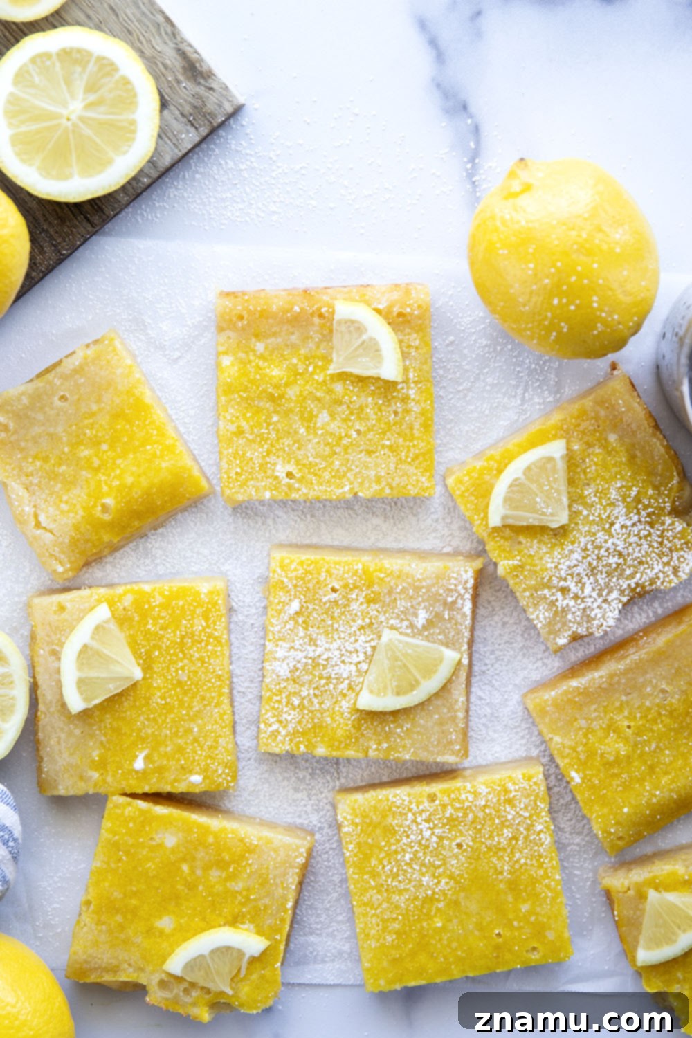 Perfect Lemon Bars 6 Six perfect lemon bars, neatly cut and arranged on a white plate, ready to be served, dusted with powdered sugar.