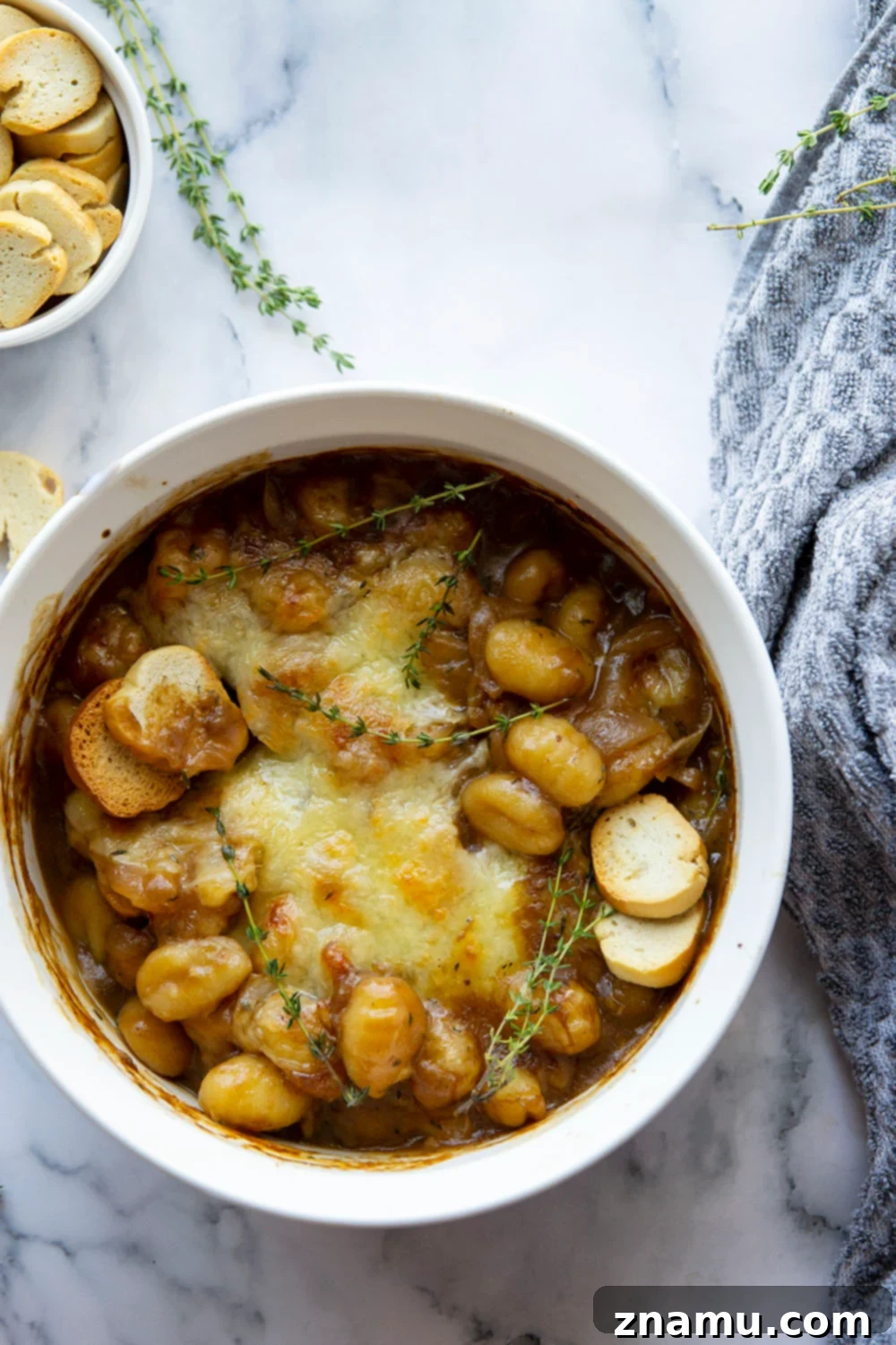 Savory Onion Gnocchi Gratin 2 This baked French onion gnocchi is like a heartier version of the classic soup! Tender gnocchi is baked in a flavorful caramelized onion beef broth with lots of rich cheese on top and French bread slices for dipping.
