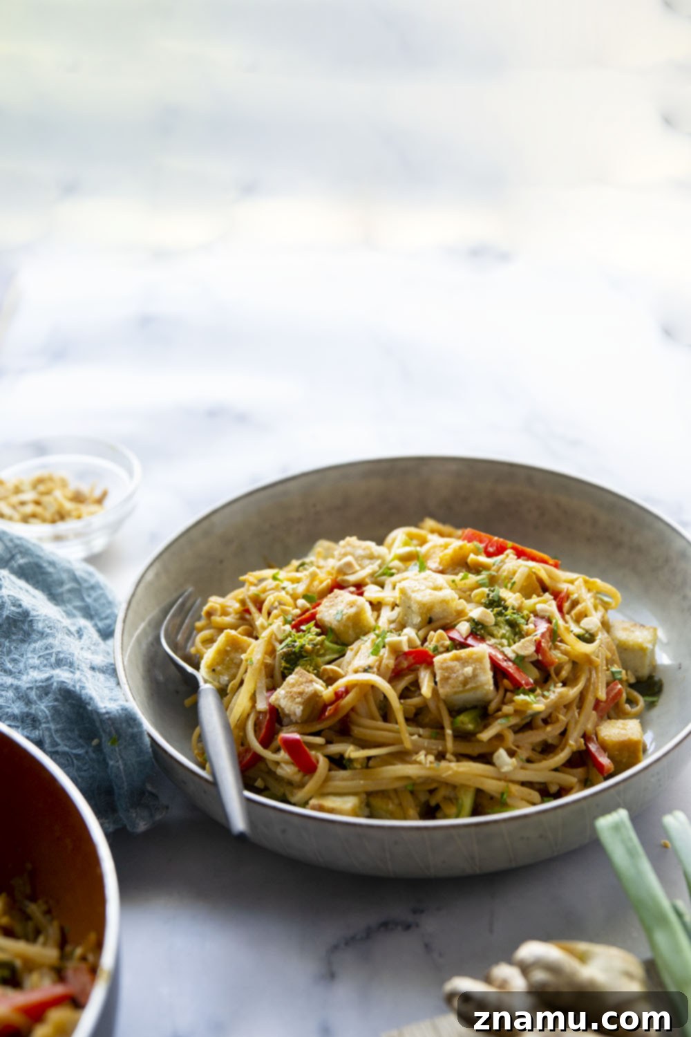 Creamy Peanut Satay Tofu Noodles 3 Overhead shot of a skillet filled with Peanut Satay Noodles, tofu, and fresh cilantro.