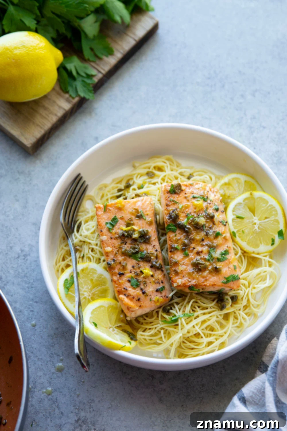 Weeknight Salmon Piccata Skillet 5 Fresh salmon fillets ready for cooking, next to garlic and capers.