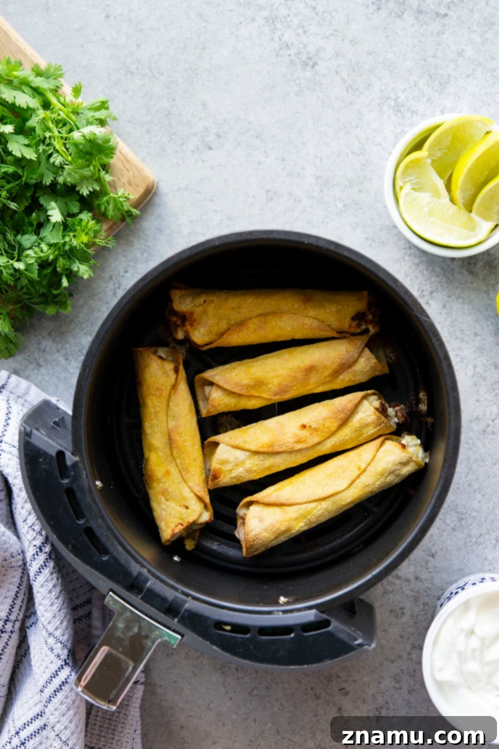 Hand rolling a green chile chicken taquito before air frying
