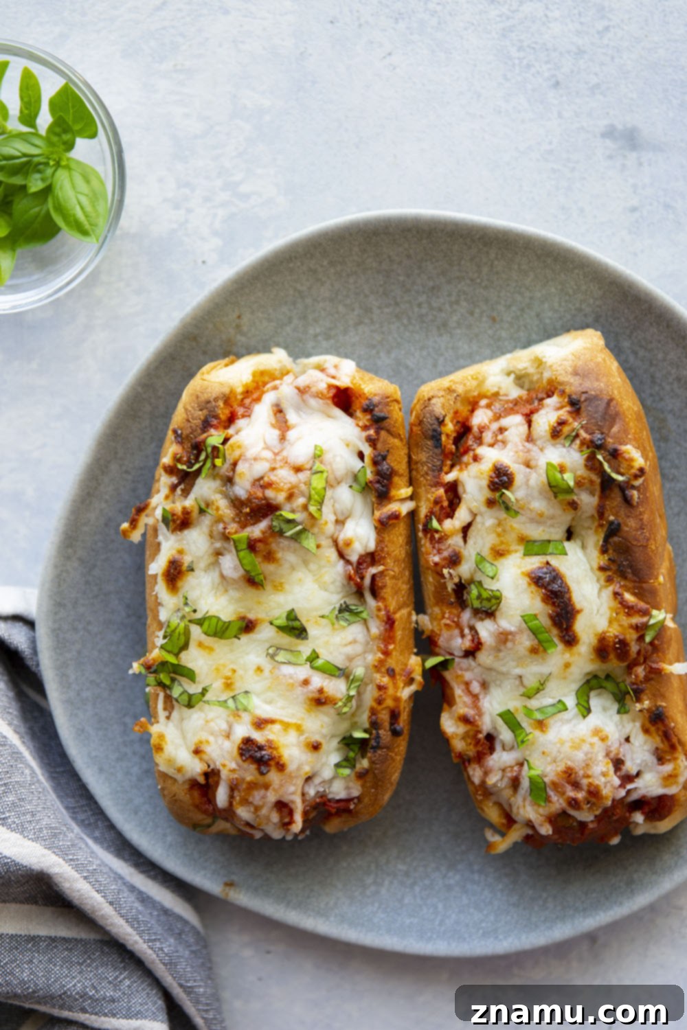 Cheesy Baked Meatball Subs 3 Close-up of baked meatball marinara subs with melted cheese and fresh basil.