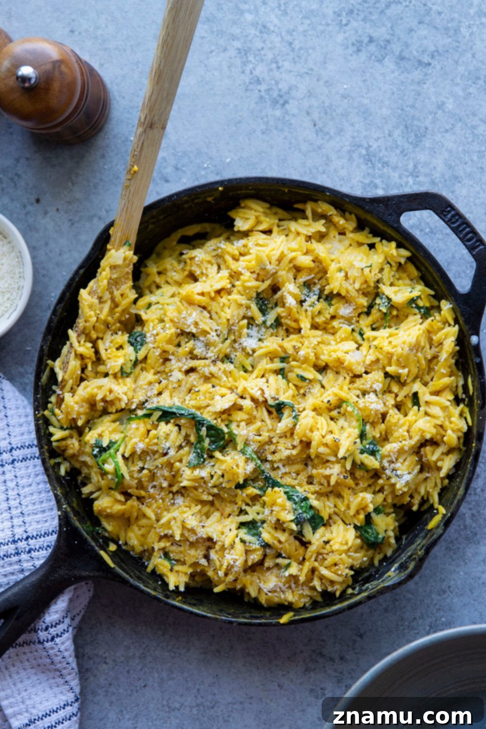 One Pot Velvety Pumpkin Orzo 6 A close-up of a fork twirling creamy pumpkin orzo, demonstrating the rich texture and readiness of the dish. Made in one pot and packed with cozy fall flavors, this creamy pumpkin orzo is perfectly cheesy, creamy, and loaded with flavorful pumpkin, wilted spinach, and tender orzo.