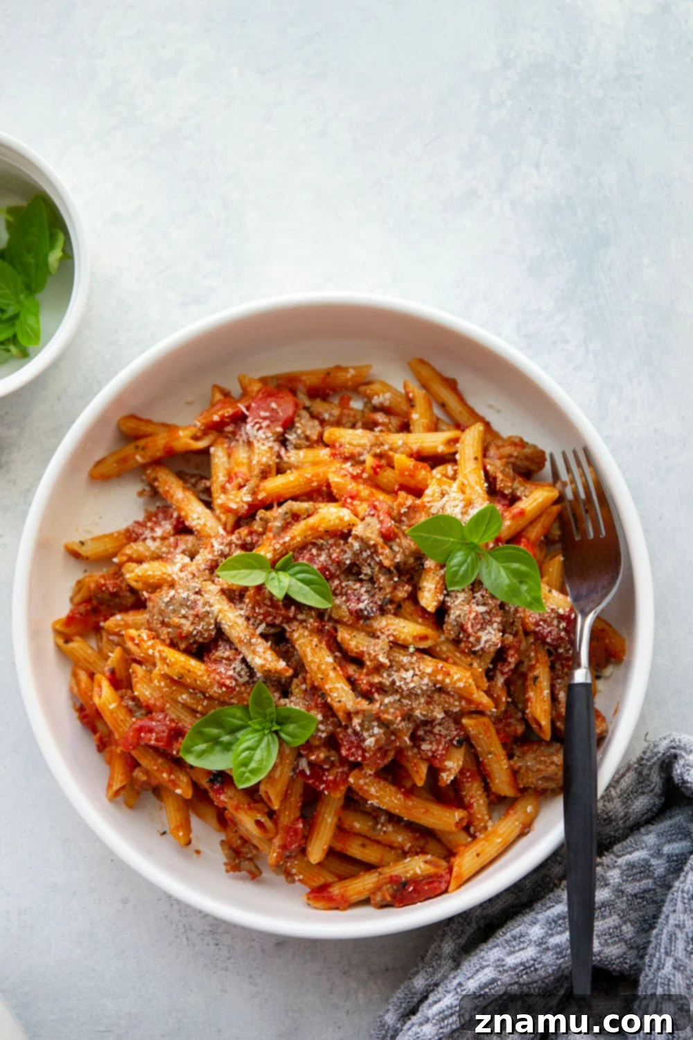 Smoky Red Pepper & Sausage Vodka Pasta 2 A close-up shot of a creamy Penne alla Vodka with Sausage in a large pot, garnished with fresh basil, showcasing the rich red sauce, pasta, and browned sausage pieces.
