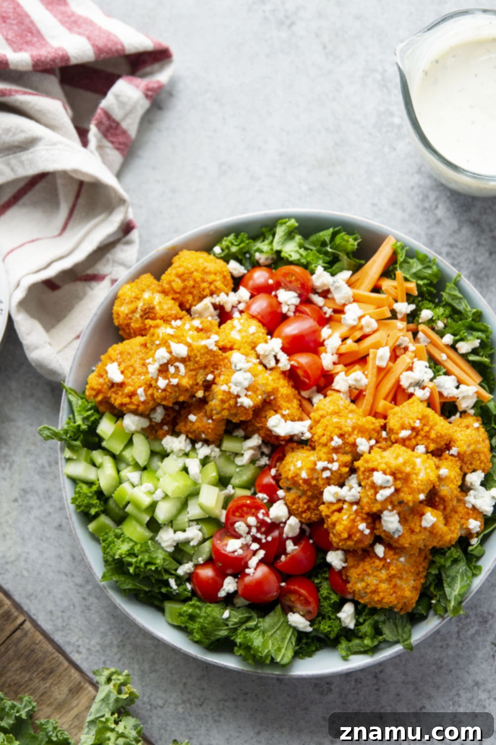 Fiery Buffalo Chicken Kale Delight 4 Overhead view of a prepared Buffalo Chicken Kale Salad with ranch dressing, ready to be served.