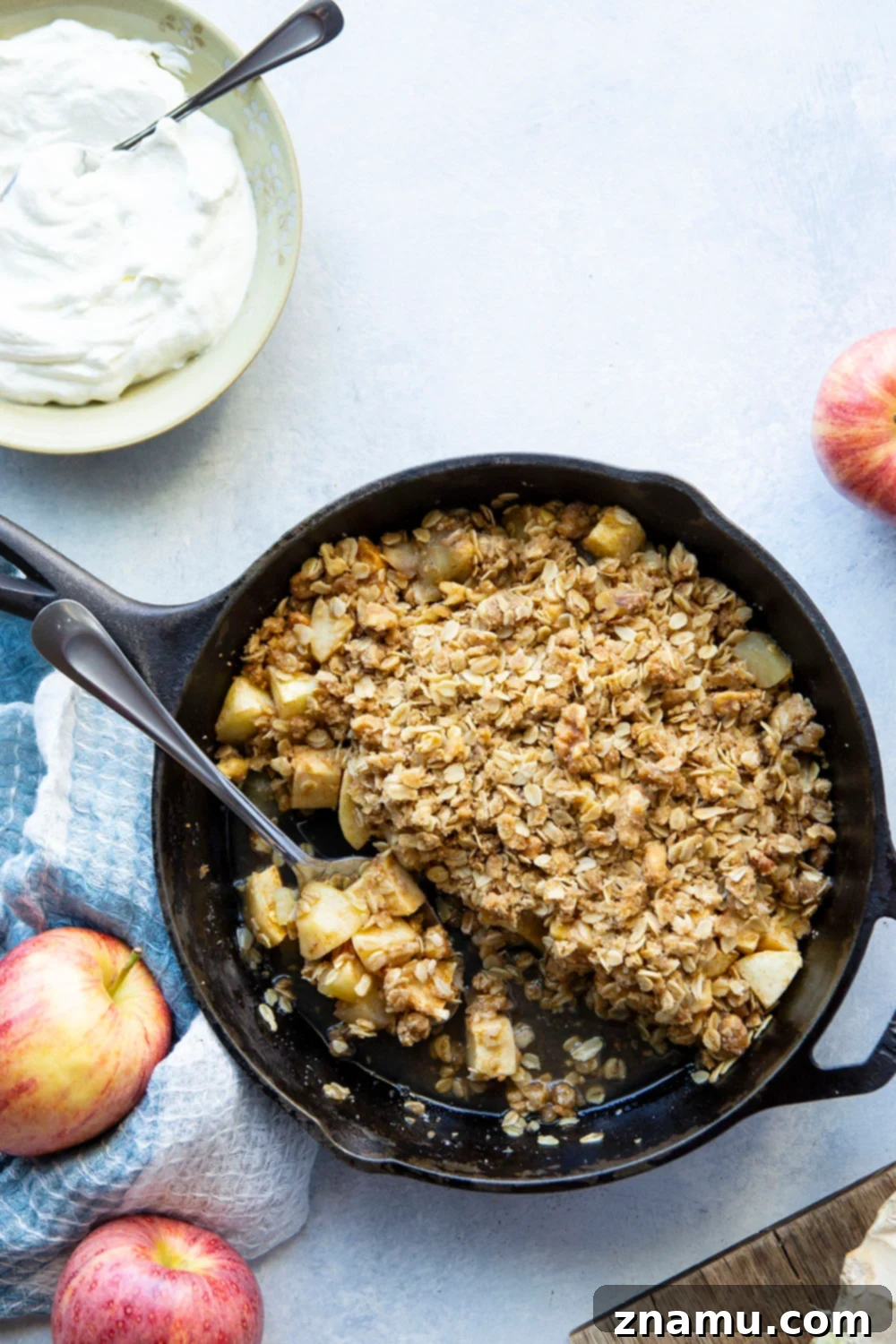 Zingy Ginger Apple Skillet Crisp 2 Close-up of a warm Skillet Ginger Apple Crisp, served in a cast iron pan, topped with melting vanilla ice cream and fresh ginger shavings.