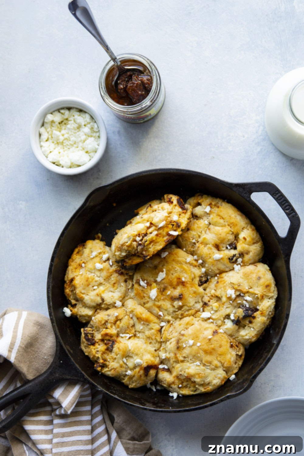 Sun-Kissed Feta Skillet Biscuits 3 Close-up of a skillet filled with freshly baked sun-dried tomato and feta biscuits, showing off their flaky layers.