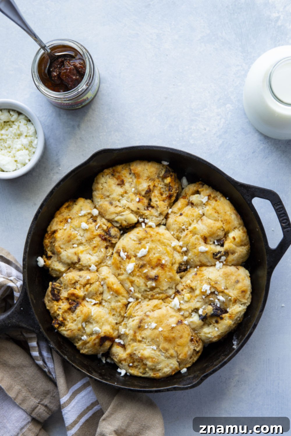 Sun-Kissed Feta Skillet Biscuits 4 A hand gently breaking open a sun-dried tomato and feta biscuit, revealing its soft, flaky interior.