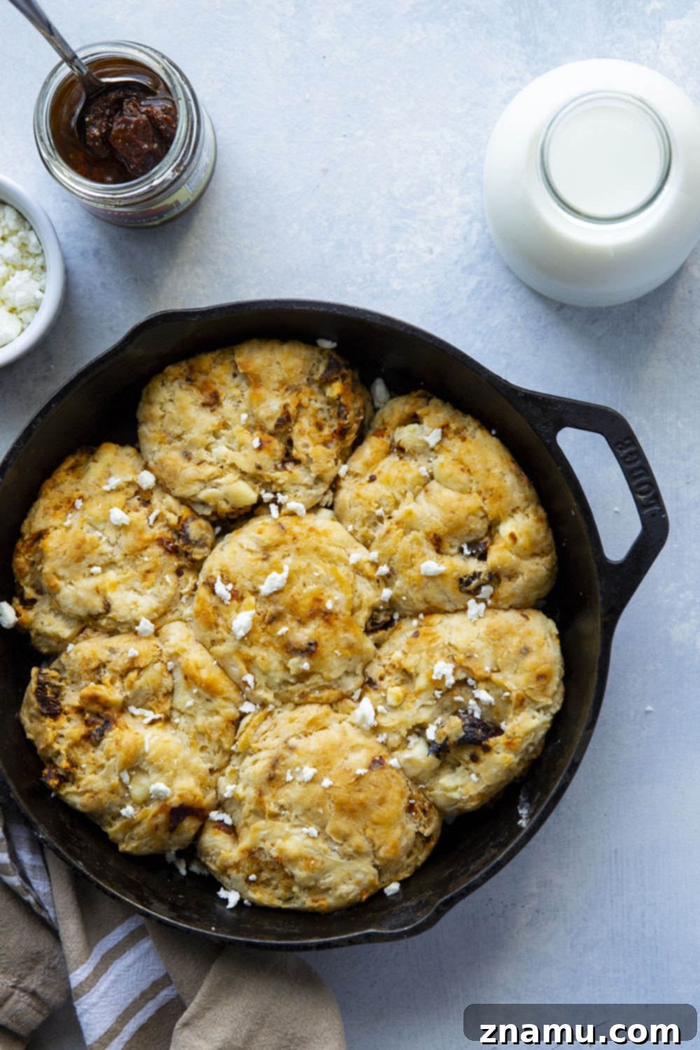 Sun-Kissed Feta Skillet Biscuits 5 Prepared biscuit dough with sun-dried tomatoes and feta, shaped and arranged in a cast iron skillet before baking.