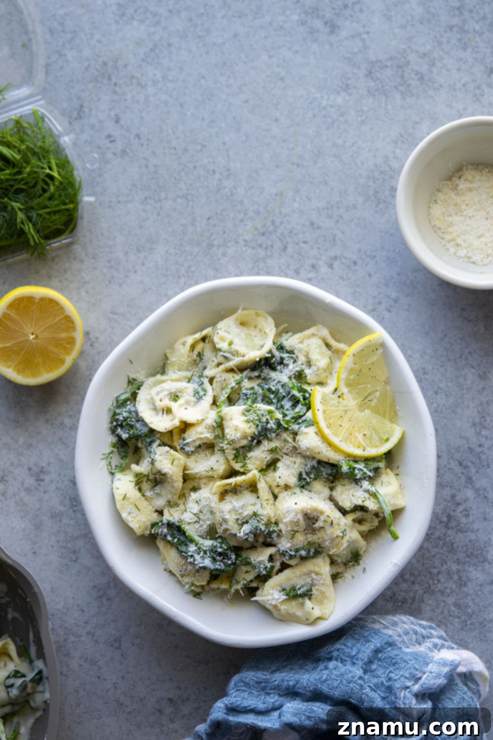Zesty Lemon Dill Alfredo Tortellini 5 Ingredients for lemon dill spinach alfredo tortellini laid out, including fresh lemon, dill, and spinach.