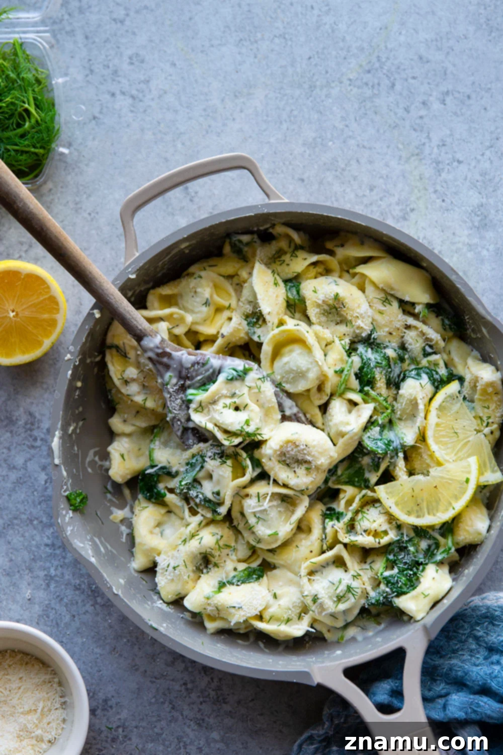 Zesty Lemon Dill Alfredo Tortellini 6 Plated lemon dill spinach alfredo tortellini with a fork, ready to be enjoyed.