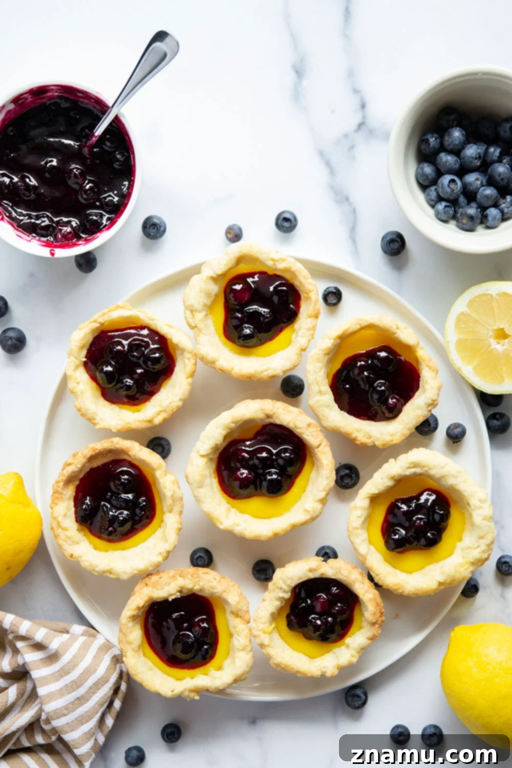 Sunshine Lemon & Blueberry Tartlets 4 A single mini lemon tart, perfectly portioned, highlighting the flaky edges of the crust, the vibrant lemon filling, and the glistening blueberry sauce.