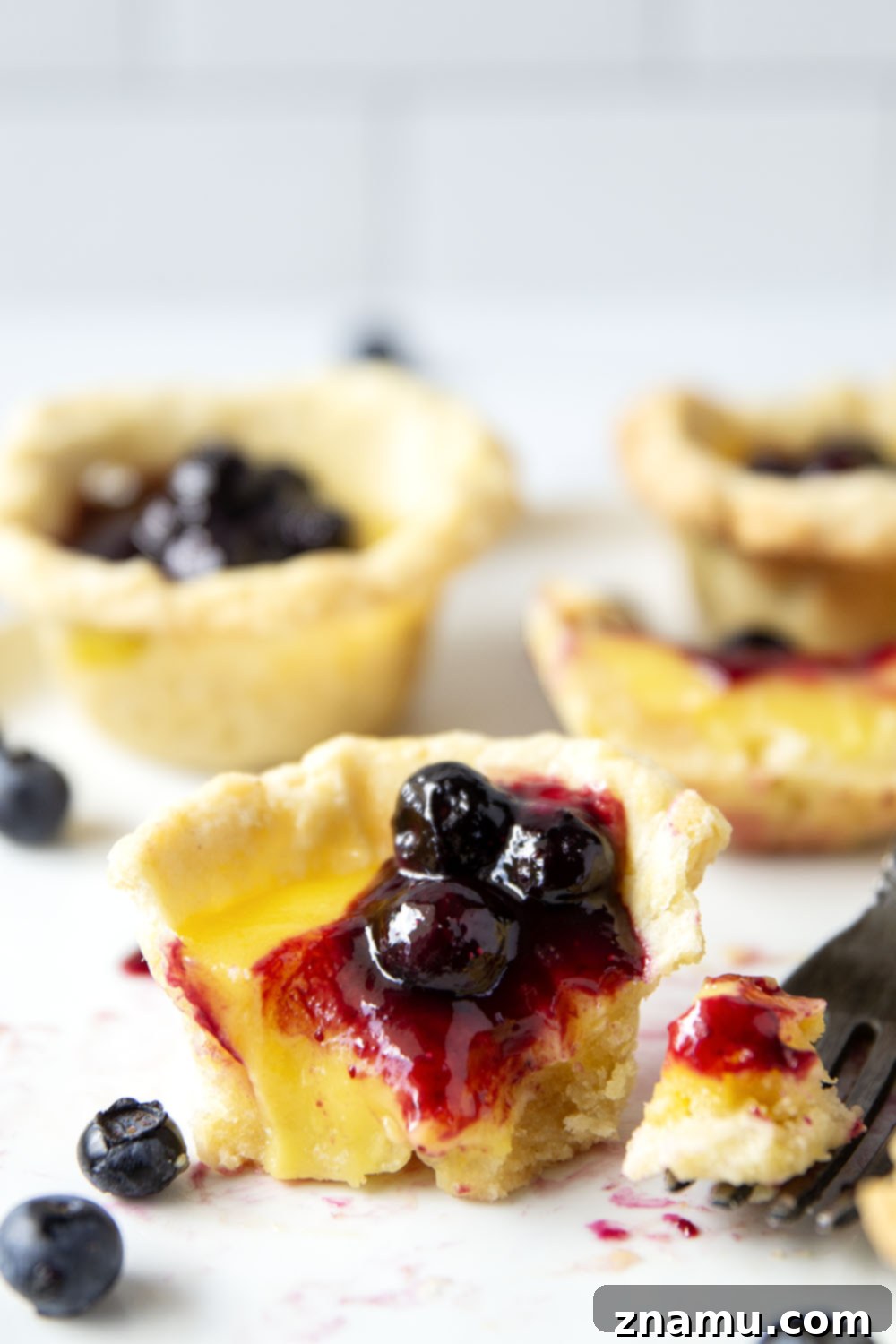 Sunshine Lemon & Blueberry Tartlets 5 A batch of par-baked mini tart crusts in a muffin pan, showing their lightly golden color, ready for the lemon filling.
