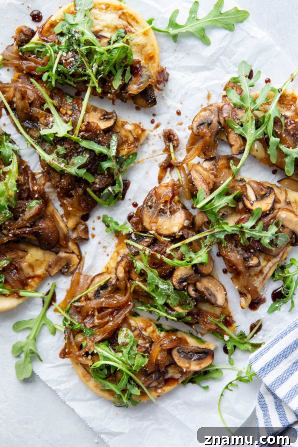 A beautifully plated Caramelized Onion Mushroom Flatbread, garnished with fresh arugula and a rich balsamic glaze, ready to be served.