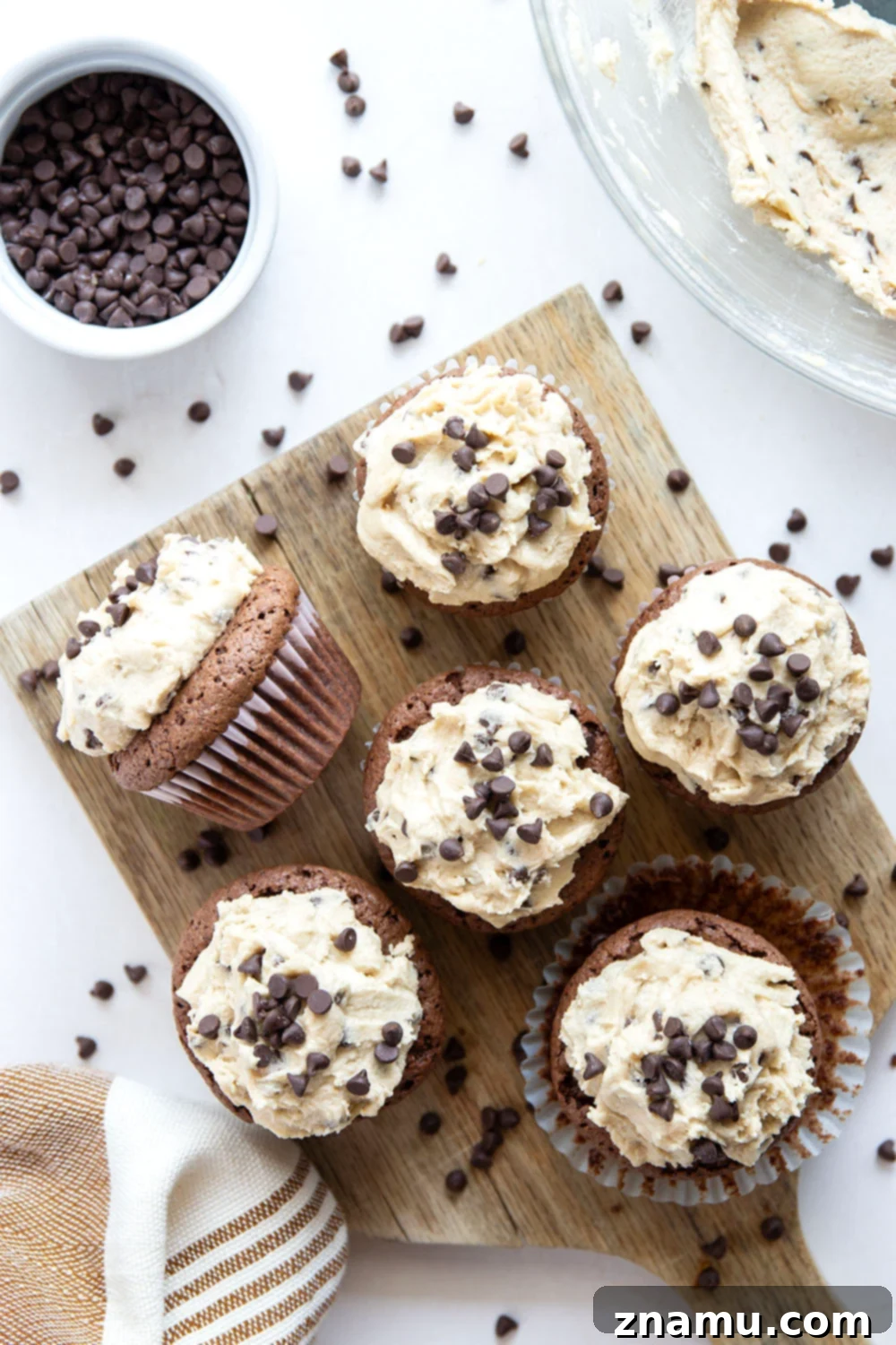 Ultimate Cookie Dough Brownie Cupcakes 6 An overhead view of several frosted brownie cupcakes, garnished with additional mini chocolate chips, ready to be enjoyed.