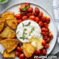 Baked until perfectly melty and topped with fresh herbs, this baked brie with cherry tomatoes is a super easy appetizer and amazing served with crostini for dipping.