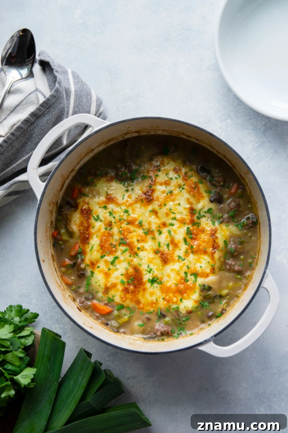 Rich White Cheddar Shepherds Pie with Leek and Mushroom Medley 4 Ingredients for Leek Mushroom Shepherd's Pie arranged on a wooden board, highlighting fresh leeks, mushrooms, and Yukon gold potatoes.