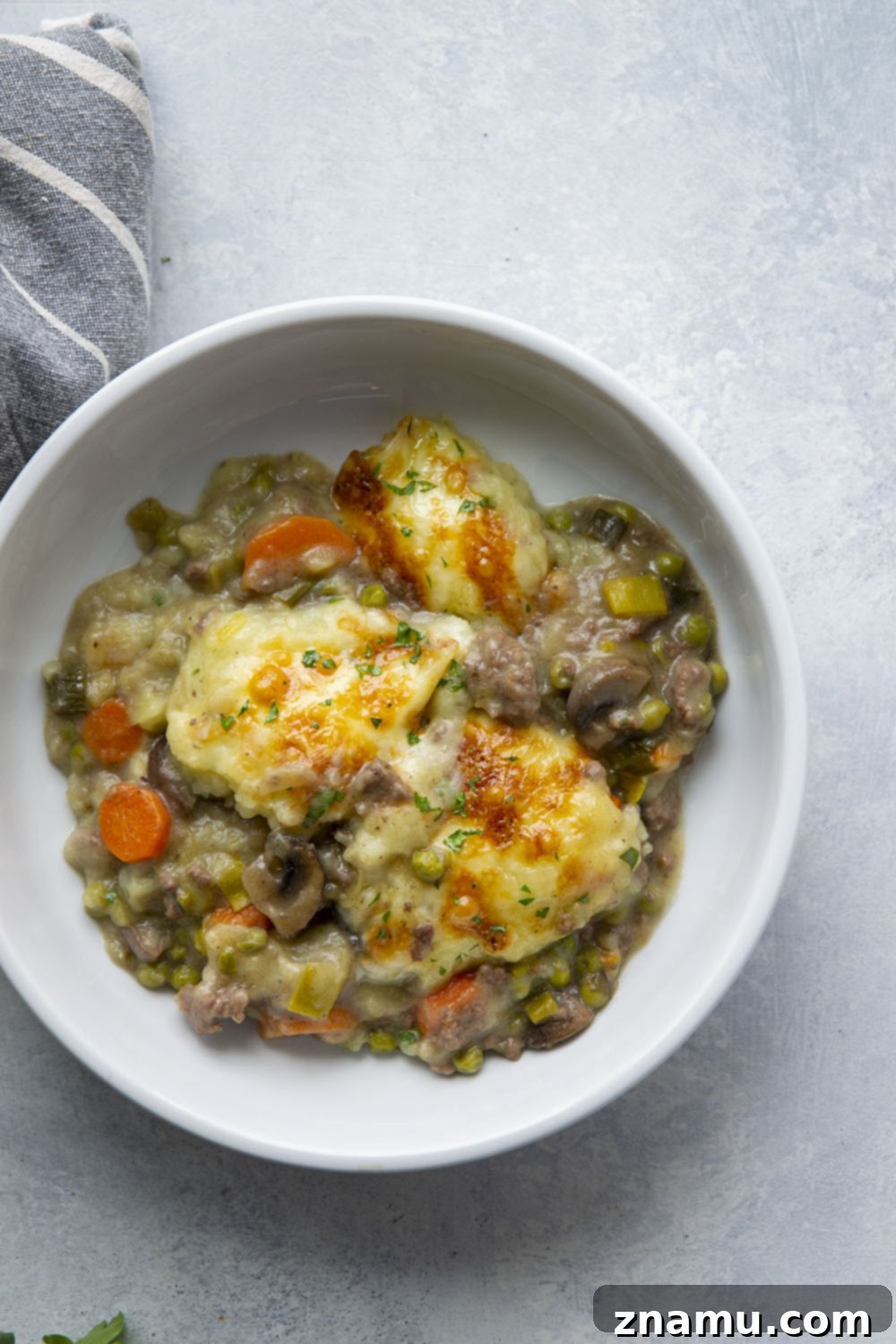 Rich White Cheddar Shepherds Pie with Leek and Mushroom Medley 5 Leek Mushroom Shepherd's Pie being spooned into a baking dish, showing the hearty beef and vegetable filling.