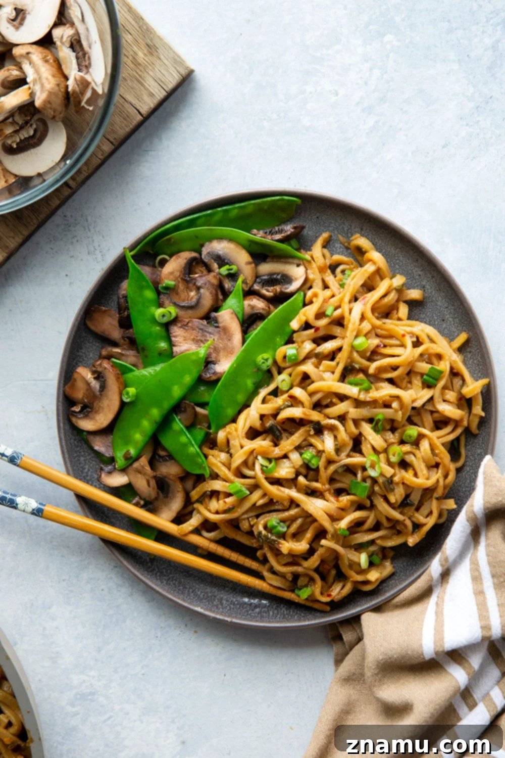Fiery Miso Scallion Noodles 2 Close-up of a bowl of spicy scallion miso noodles with sautéed mushrooms and snow peas, garnished with fresh green onions.