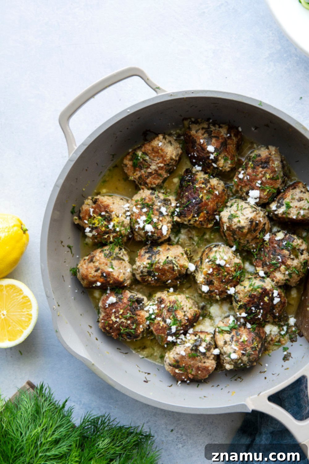 Zesty Lemon Dill Chicken Meatballs with Spinach and Feta 3 Close-up of golden brown spinach feta chicken meatballs simmering in a creamy lemon dill sauce.