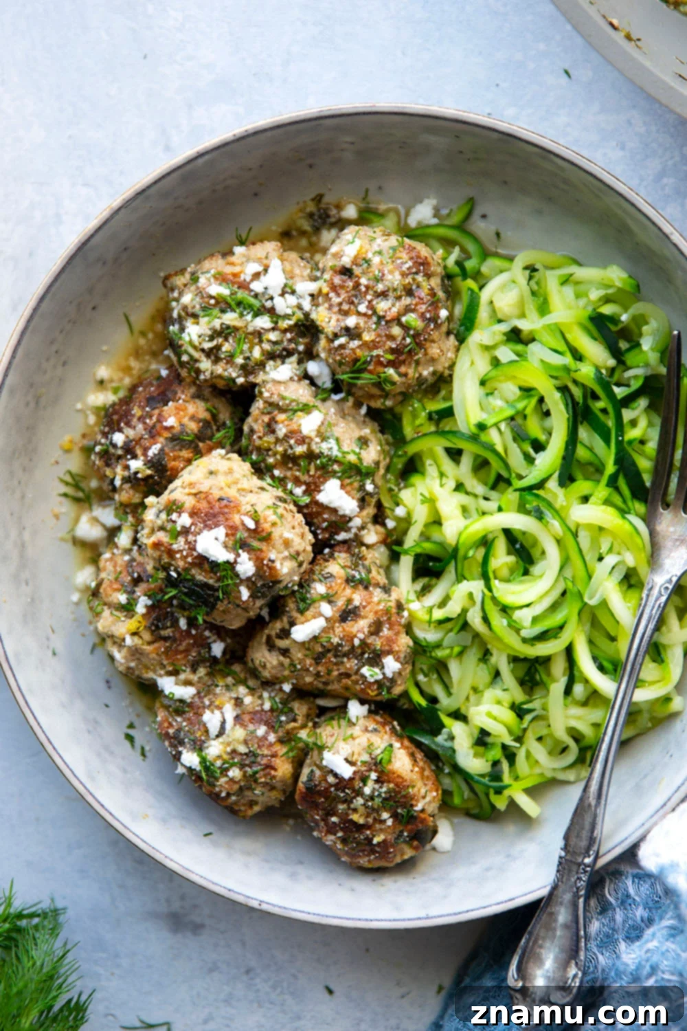 Zesty Lemon Dill Chicken Meatballs with Spinach and Feta 4 A serving of spinach feta chicken meatballs plated with zucchini noodles and fresh dill garnish.