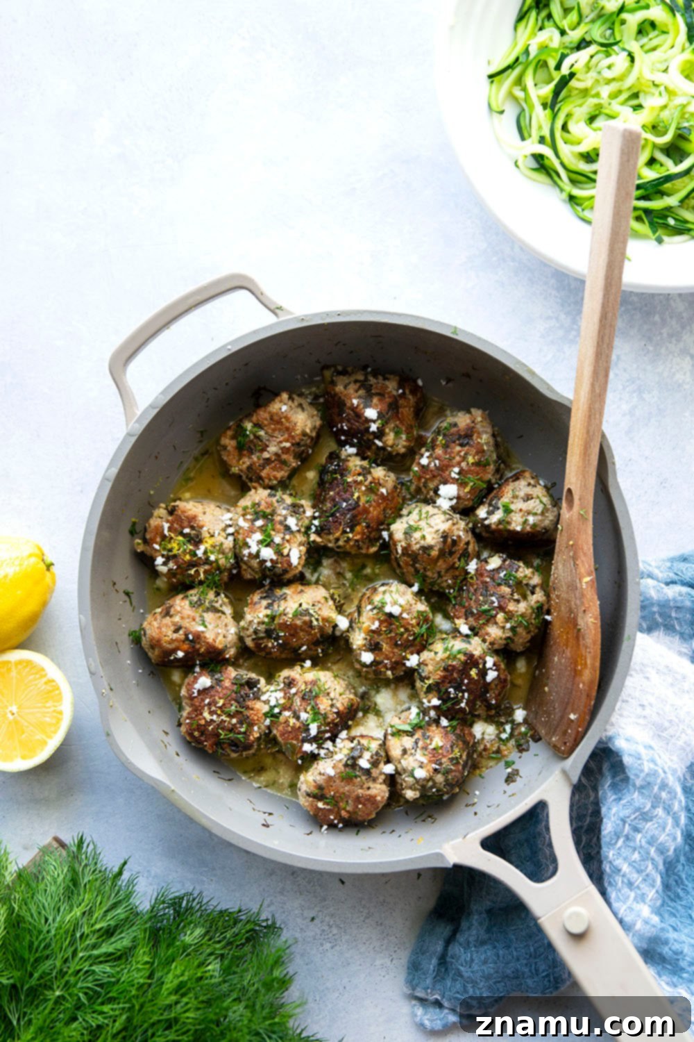 Zesty Lemon Dill Chicken Meatballs with Spinach and Feta 6 A close-up shot of spinach feta chicken meatballs in lemon dill sauce, garnished with fresh dill.