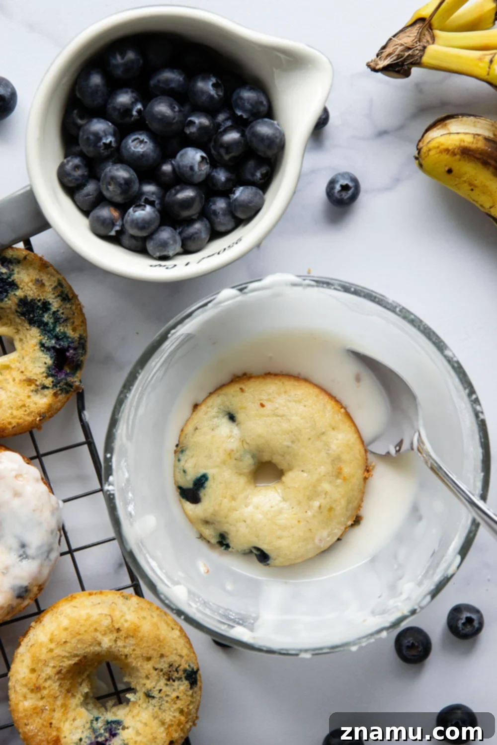 Blueberry Banana Vanilla Donuts 3 A stack of three freshly baked blueberry banana donuts on a plate, showcasing their inviting golden-brown crust and fluffy texture, before being glazed.