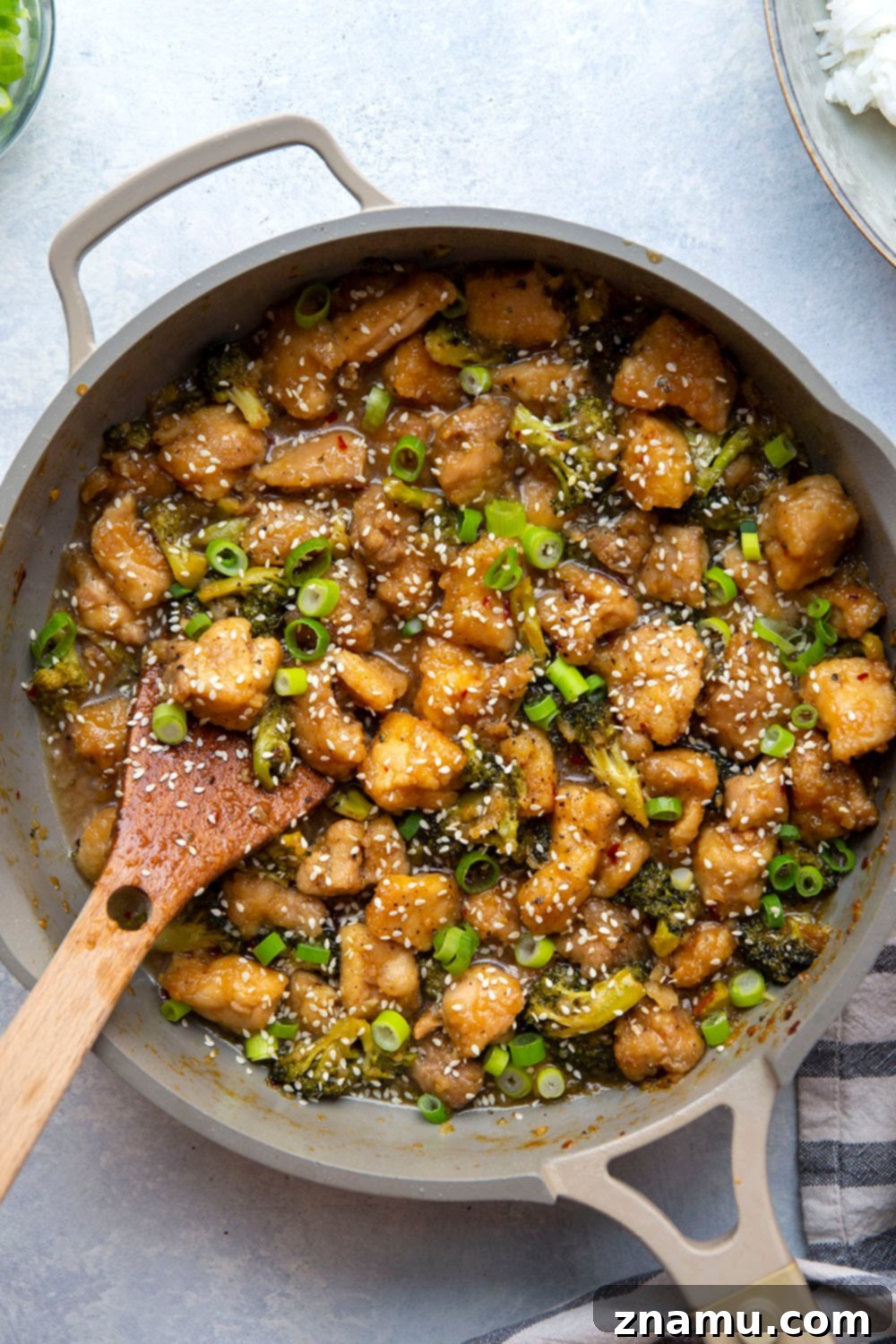 Sticky Honey Bourbon Chicken and Broccoli 2 Close-up of a plate of Honey Bourbon Chicken and Broccoli served with rice, garnished with green onions and sesame seeds.