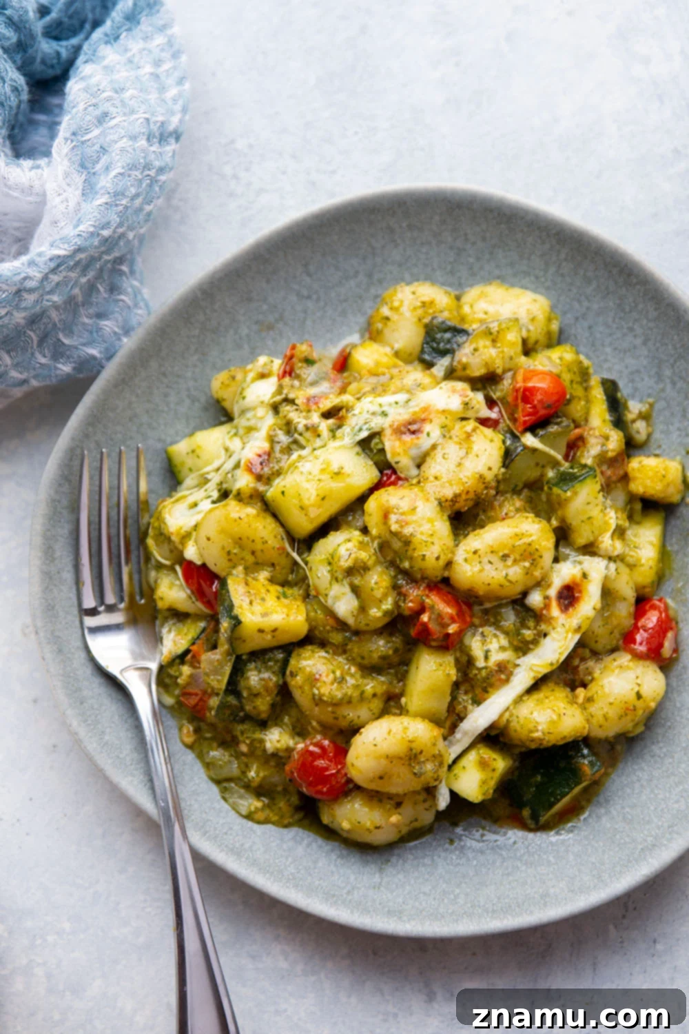 Baked with two kinds of cheese on top with lots of tender zucchini and cherry tomatoes, this cheesy baked pesto gnocchi uses basic pantry ingredients and is ready in under an hour!