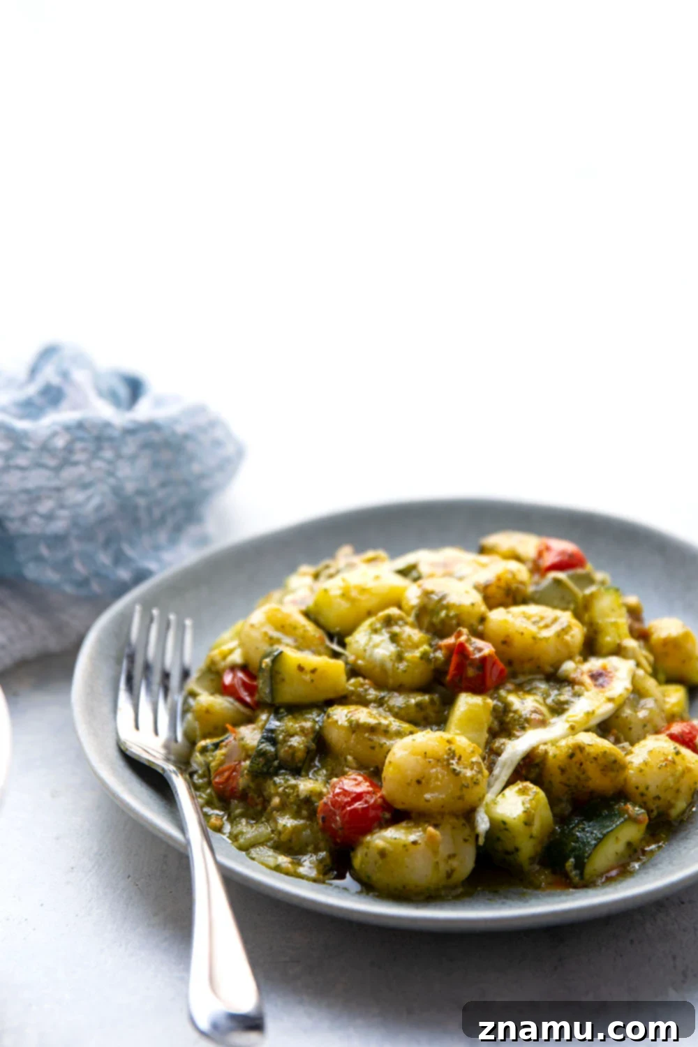 Baked with two kinds of cheese on top with lots of tender zucchini and cherry tomatoes, this cheesy baked pesto gnocchi uses basic pantry ingredients and is ready in under an hour!