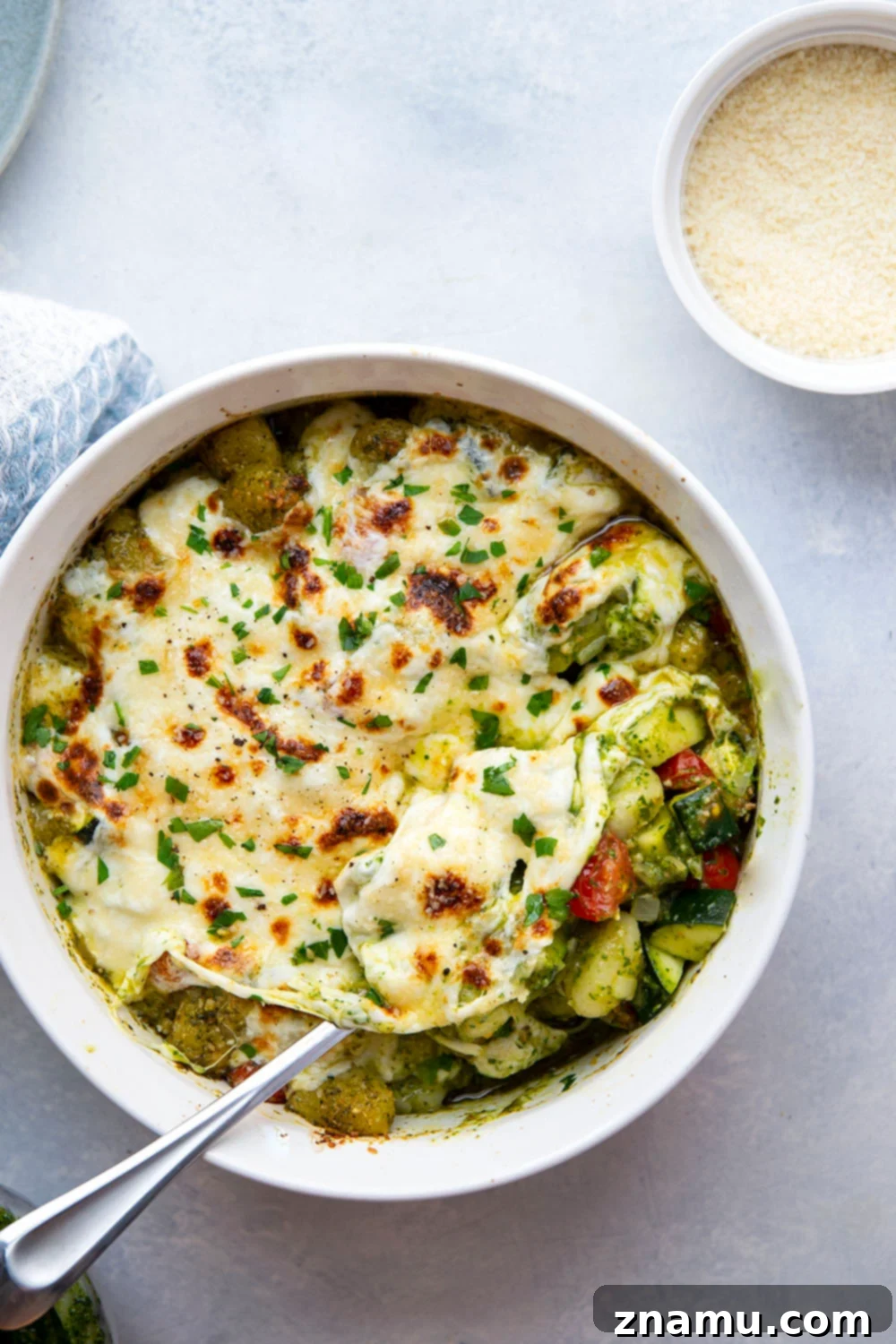 Baked with two kinds of cheese on top with lots of tender zucchini and cherry tomatoes, this cheesy baked pesto gnocchi uses basic pantry ingredients and is ready in under an hour!