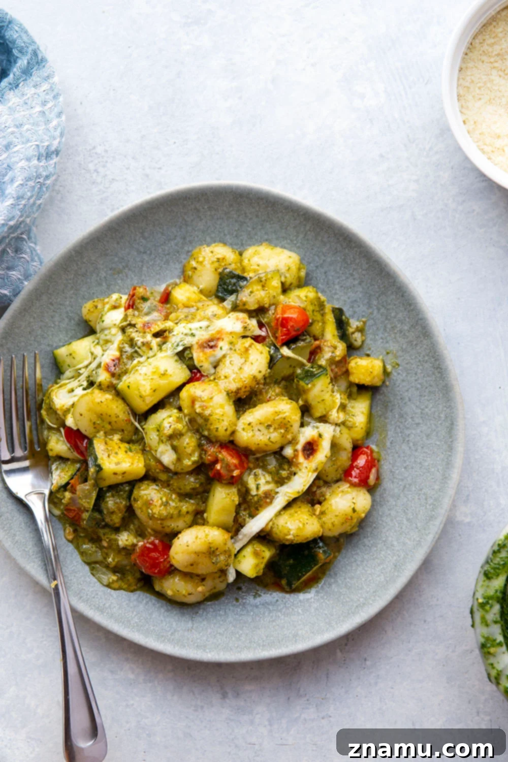 Baked with two kinds of cheese on top with lots of tender zucchini and cherry tomatoes, this cheesy baked pesto gnocchi uses basic pantry ingredients and is ready in under an hour!