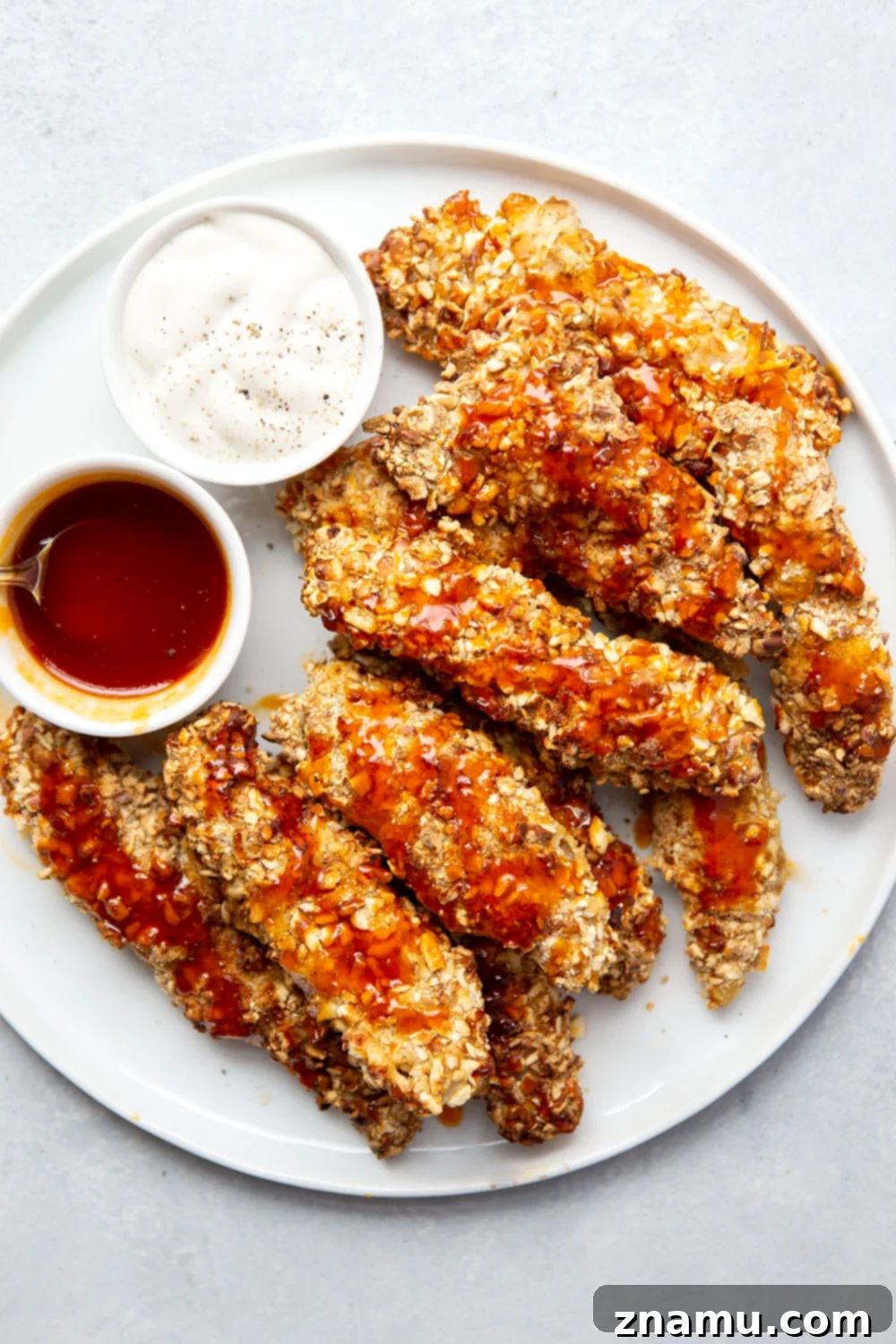 Air Fryer Crispy Pretzel Chicken with Hot Honey Glaze 4 Three shallow bowls showing the breading station: flour, egg wash, and crushed pretzels mixed with seasoning.