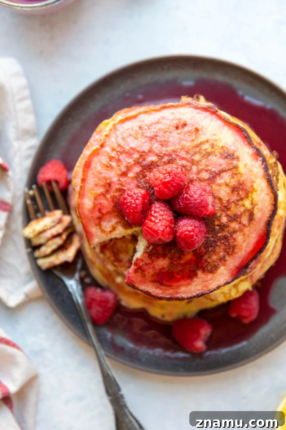 Fluffy Lemon Cottage Cheese Pancakes with Raspberry Drizzle 6 A beautifully presented stack of fluffy lemon cottage cheese pancakes, topped with a generous pour of rich, homemade raspberry syrup and scattered with fresh raspberries. The pancakes are on a light plate, with a fork gently resting, inviting the viewer to indulge. The image perfectly captures the soft texture and vibrant flavors of this gluten-free and protein-rich breakfast.