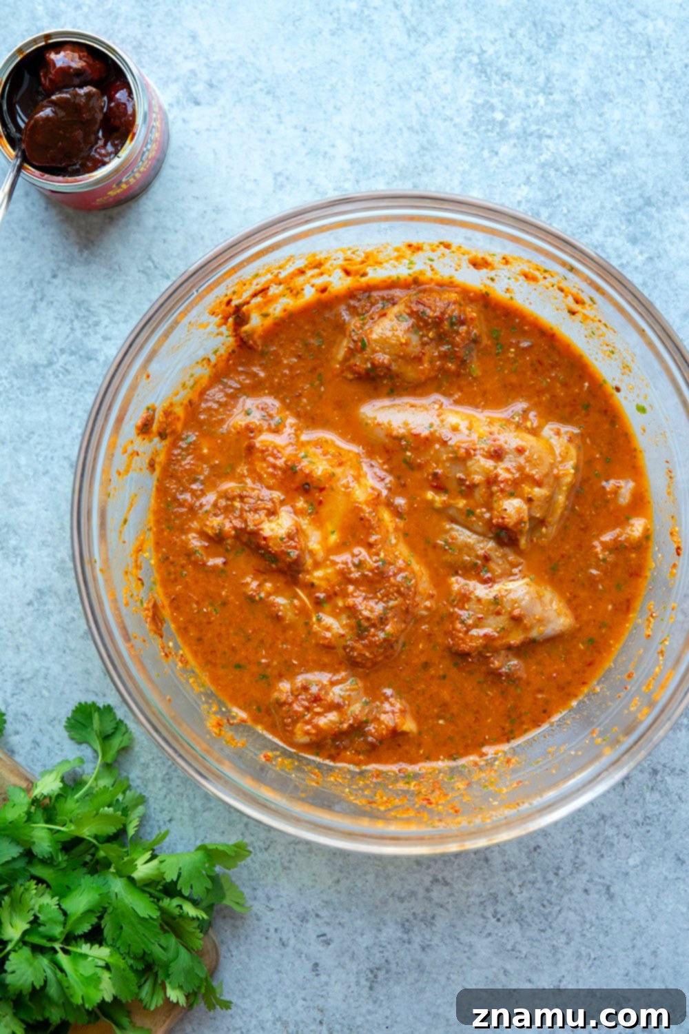 Smoky Chipotle Grilled Chicken Thighs 4 Chipotle marinated raw chicken thighs in a bowl.