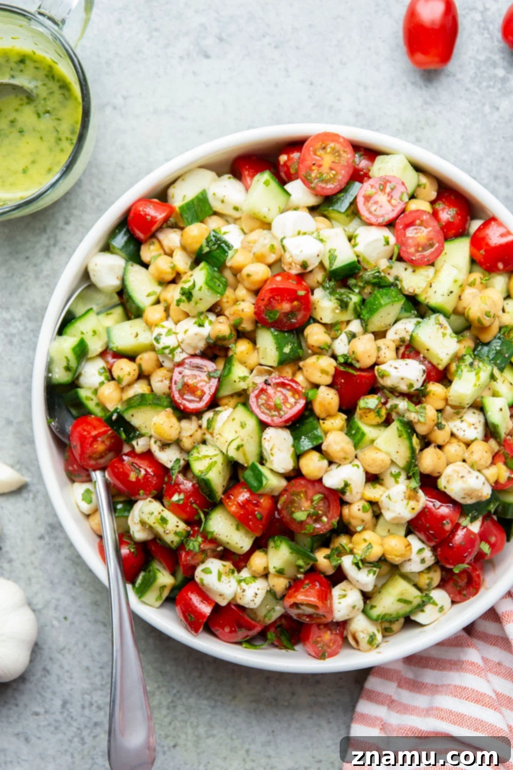 Roasted Garlic Basil Caprese Chickpea Salad 4 Ingredients for the roasted garlic basil dressing laid out: whole garlic cloves, fresh basil leaves, olive oil, white wine vinegar, and honey.