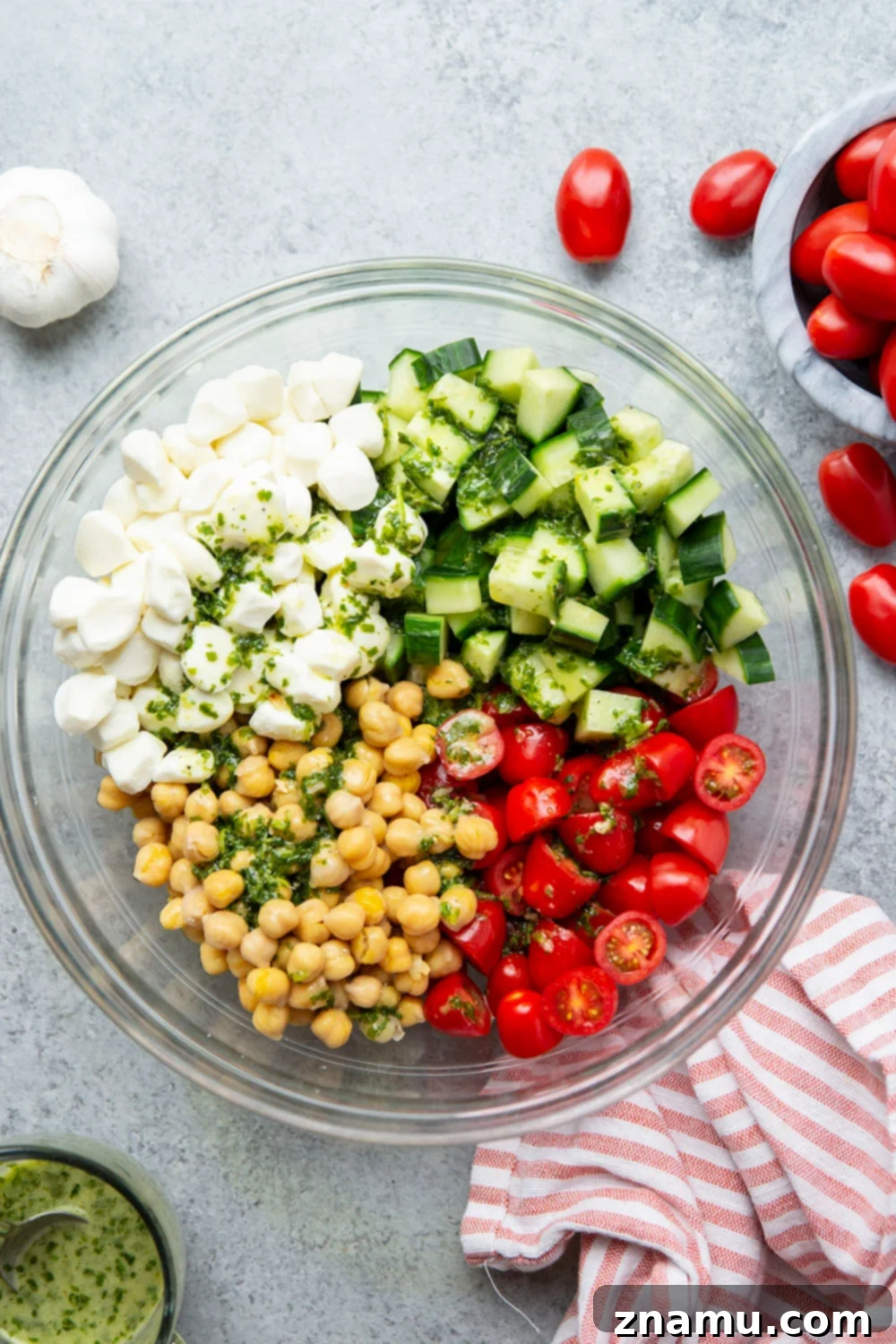 Roasted Garlic Basil Caprese Chickpea Salad 5 Caprese Chickpea Salad presented in a light blue bowl, garnished with extra fresh basil and a drizzle of balsamic glaze, ready to be served.