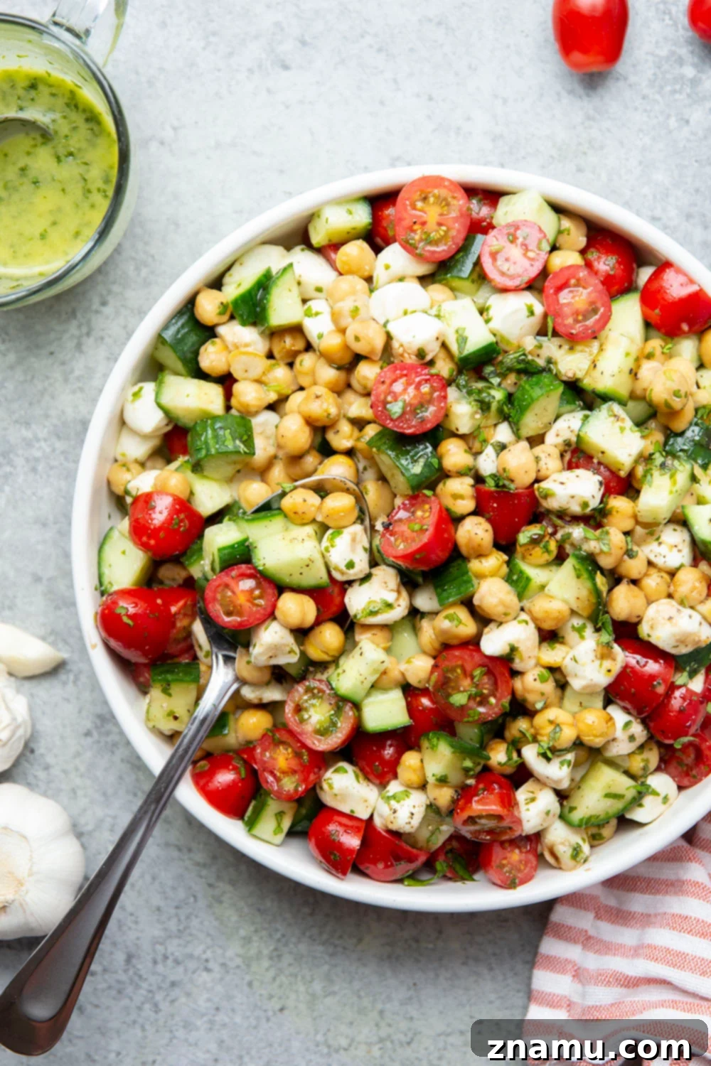 Roasted Garlic Basil Caprese Chickpea Salad 6 A large bowl of Caprese Chickpea Salad with a serving spoon, highlighting the generous portions and vibrant mix of ingredients.
