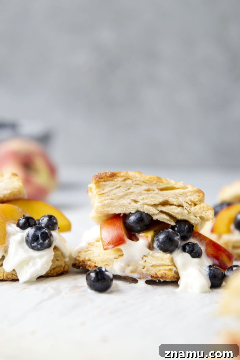 Sun-Drenched Peach Berry Dream 4 A close-up of a blueberry peach shortcake, highlighting the golden brown, perfectly baked biscuit texture, with hints of fruit and cream. An inviting photo for a delicious summer dessert recipe.
