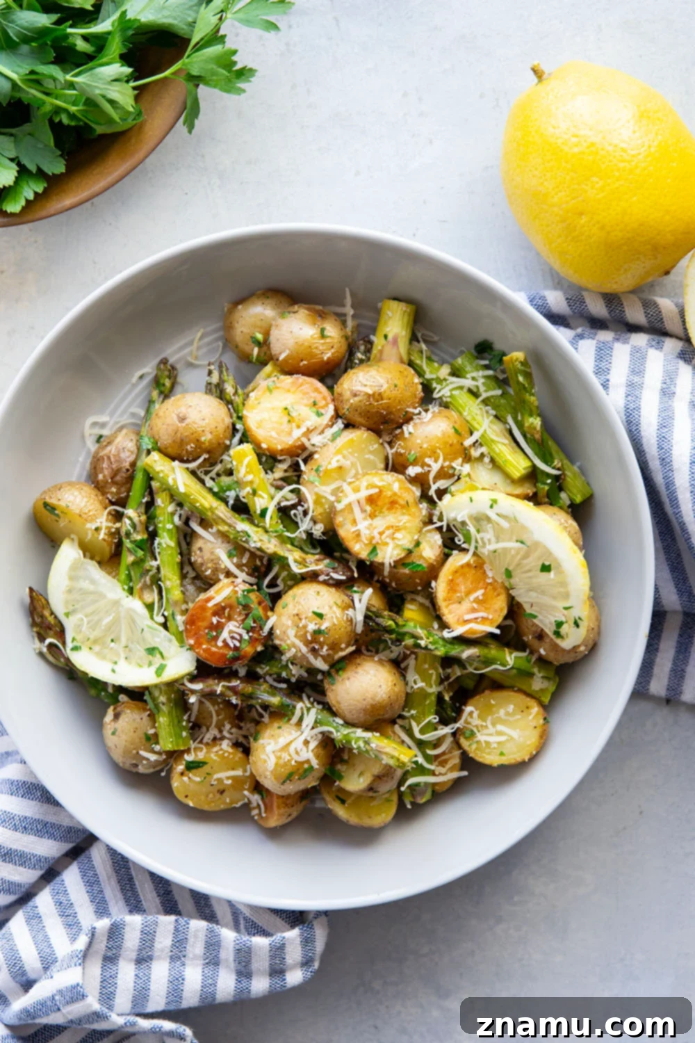 Bright Lemon Roasted Asparagus and Potatoes 2 Close-up of vibrant lemon roasted potatoes and asparagus on a sheet pan, garnished with fresh parsley.