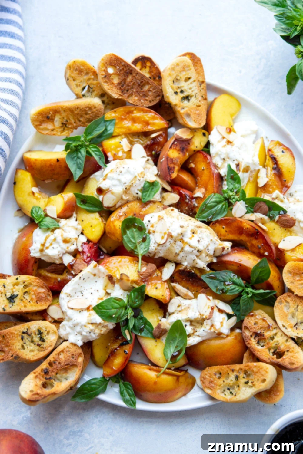 Smoky Grilled Peaches with Creamy Burrata 4 Overhead shot of a platter with grilled peaches, burrata, basil, and crostini.